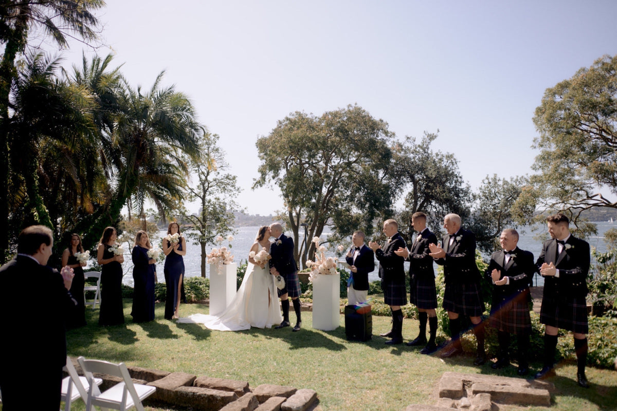 Couple at their outdoor ceremony at McKell Park with floral arrangements and harbour views