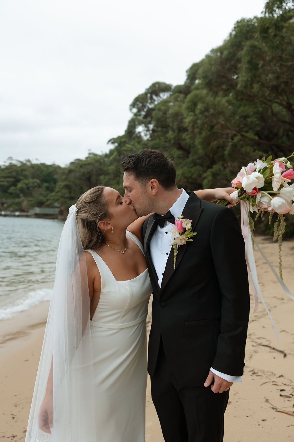 Sami and George on the beach below Athol Hall with a blush and white bouquet
