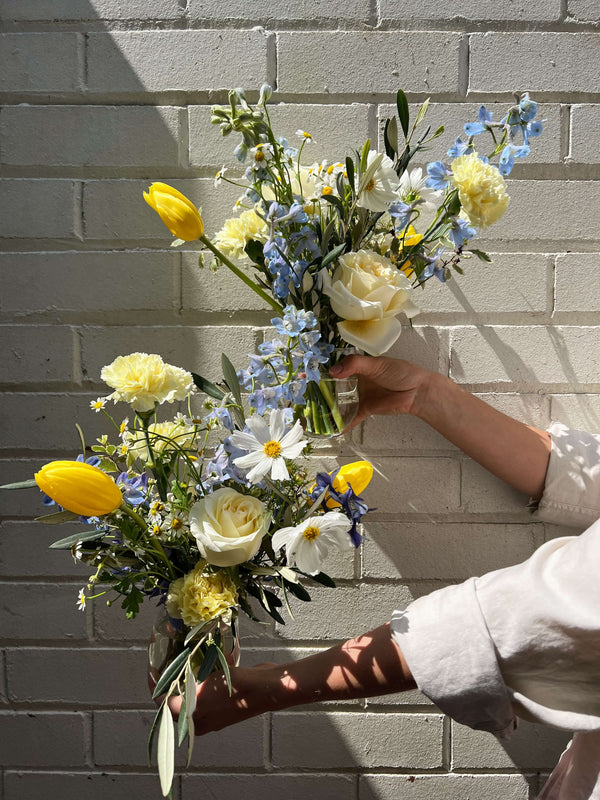blue yellow flower arrangement in vase for an event in sydney against white brick wall